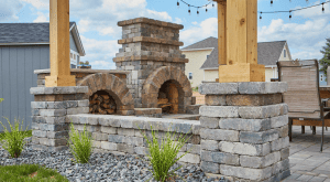 Outdoor stone fireplace with stacked wood and pergola posts.