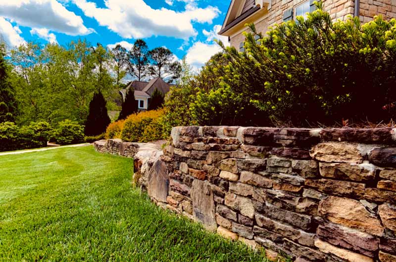 Stone retaining wall beside a landscaped lawn